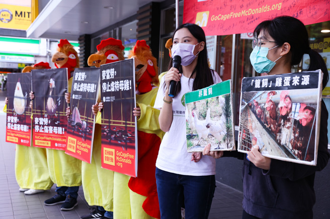 亚洲动保组织21日联合在亚洲八个国家速食店门市外高举连署布条，台湾动物社会研究会发言人寸舫筑（右二）表示，麦当劳在美加、拉丁美洲、纽澳、南非都已承诺改用非笼饲鸡蛋，依此要求亚洲门市也应逐步落实全面採用非笼饲鸡蛋。（罗永铭摄）