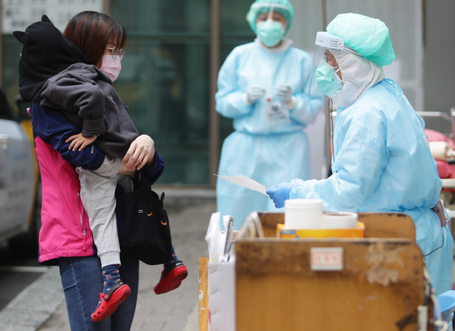 国内目前出现3起儿童新冠肺炎併发脑炎重症案例，中央流行疫情指挥中心表示，已研拟出一套指引，盼能解决儿童神经学重症的问题。图为家长抱着孩子到快筛站，向医护人员询问事情。（资料照／季志翔摄）