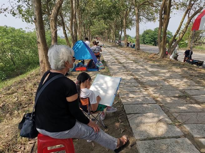 台南市安定區公所於蘇厝滯洪池旁阿勃勒花道辦寫生比賽，吸引上百名眾報名參加。（劉秀芬攝）
