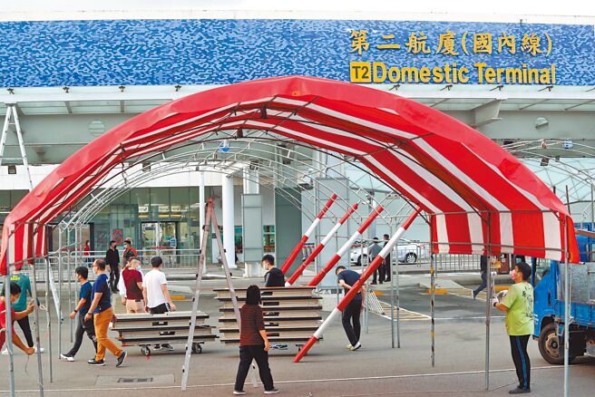 新冠肺炎疫情持续蔓延，松山机场将增设筛检站，工作人员20日在机场外的停车场搭建帐篷。（郑任南摄）