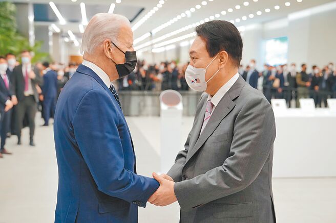 美國總統拜登20日飛抵韓國，第一站造訪三星電子半導體工廠，拜登（左）與在門口迎接的韓國總統尹錫悅（右）握手致意。（摘自美國總統拜登推特）