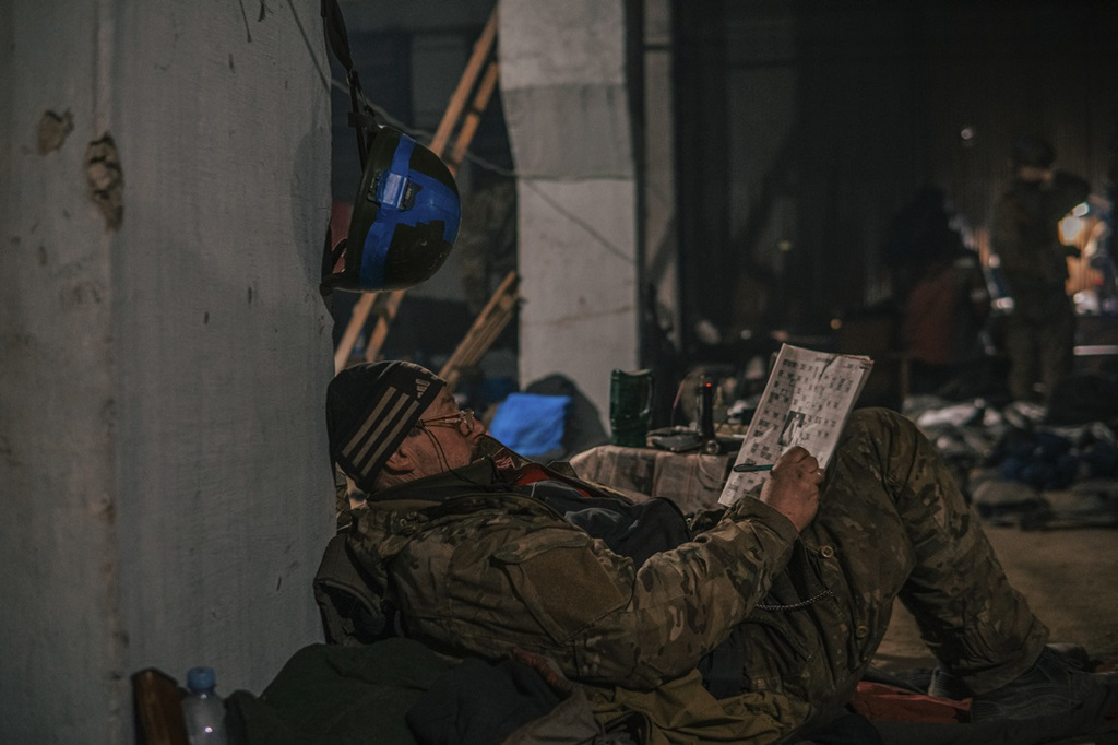 乌军科扎茨基（Dmytro Kozatsky）7日拍下一名同袍在亚速钢铁厂内休息时玩填字游戏的画面。（图／美联社、亚速军团）(photo:ChinaTimes)