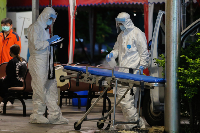 部分确诊者因发病病程快速，在确诊后数天内死亡。图为救护车队员在医院急诊处清消使用后的移动担架。（陈麒全摄）