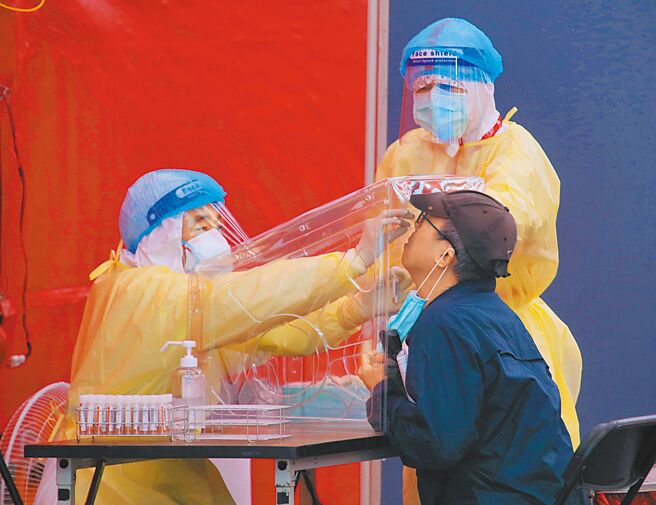 台大公衛教授詹長權建議新冠肺炎納全民健保，將快篩試劑等防疫物資轉成處方，絕對比拿健保卡去藥局排隊好。圖為松山機場篩檢站外，醫護人員穿著防護衣幫民眾採檢。（陳君瑋攝）