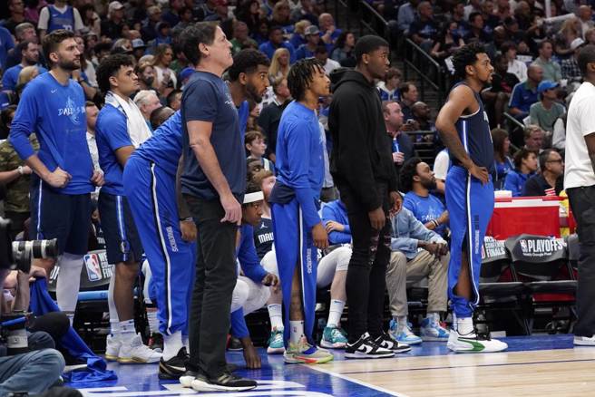 独行侠老板库班在板凳席和球员一起站着看比赛。（美联社）