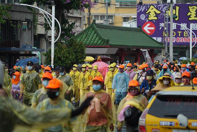 「粉红超跑」着雨衣继续赶路，不过再大的雨都浇不熄香灯脚的热情，上万信眾与妈祖一同着雨衣继续前行。（吴建辉摄）
