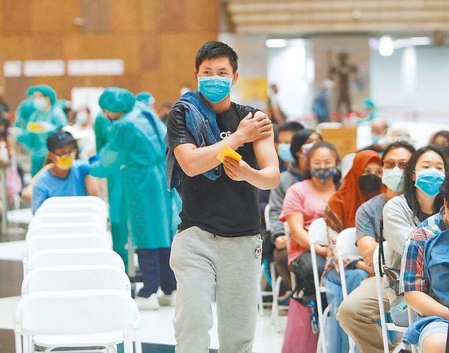 北市兒童BNT即將開打，有意願接種兒童BNT者高達1萬107人，約占51％，比預估數高。圖為民眾至北車疫苗施打站施打莫德納疫苗後壓著注射的手臂離開。（陳怡誠攝）