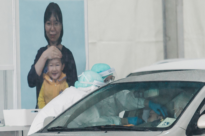疫情持续蔓延，即便下雨仍有民眾排队筛检。（郭吉铨摄）