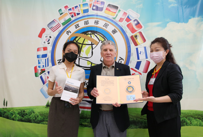 美国诗人乔直(中)申获外侨永久居留证-梅花卡，感谢他在臺讲学作育英才。右为移民署北区事务大队臺北市服务站视察洪湘凤，左为专员曾洁如。(移民署台北市服务站提供)