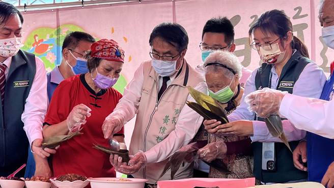 台南市长黄伟哲（中）26日与当地103岁的人瑞黄方彩华阿嬷（右三），一起用莲子等馅料绑莲粽」。（张毓翎摄）