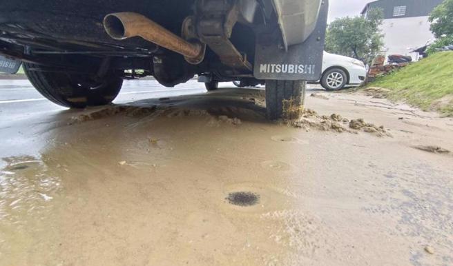 苗栗县通霄镇通湾里台1线旁一处工地25日晚间经大雨冲刷后，泥流涌入路面，造成4部机车打滑摔车，2人送医幸无大碍，包商连夜清除，至26日仍可见泥土淤积。（图/ 中央社）