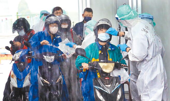 新冠肺炎疫情持续延烧，中央流行疫情指挥中心将放宽全民适用「快筛阳视同确诊」，新制上路可望加速口服抗病毒药物开立。图为北市自由广场的防疫急门诊车来速PCR筛检站内，快筛阳民眾冒雨前来採检领药。（范扬光摄）