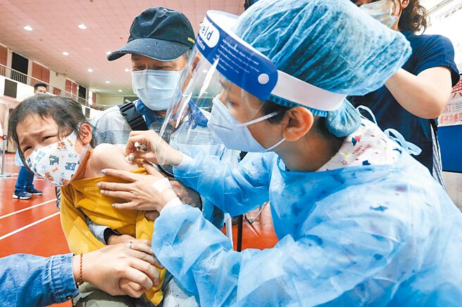 5至11岁儿童BNT疫苗25日起全国陆续开打，桃园市部分学童在东门国小校园集中接种。前来打疫苗的儿童，有人淡定，有人要父母抱抱才肯打，还有部分怕打针的儿童，在现场医护人员与陪同家人好言劝说下，才哭着完成疫苗接种。（陈麒全摄）