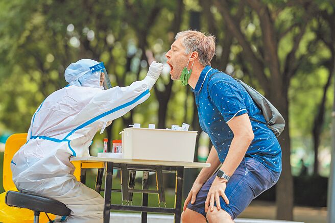 两岸航班往返将实施最新核酸检测规定，大陆官方要求从5月30日起，入境大陆或从大陆返回台湾的两岸航班，乘客都必须在起飞前48小时内完成二次核酸检测报告。图为北京医护人员陈俊华为一名外国人做採样。（中新社）
