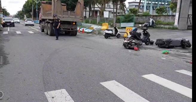 太昌国小大门口，林姓男子驾驶的砂石车，不慎与同方向的电动自行车发生擦撞，路旁两部机车也遭波及，现场凌乱。（翻摄画面)