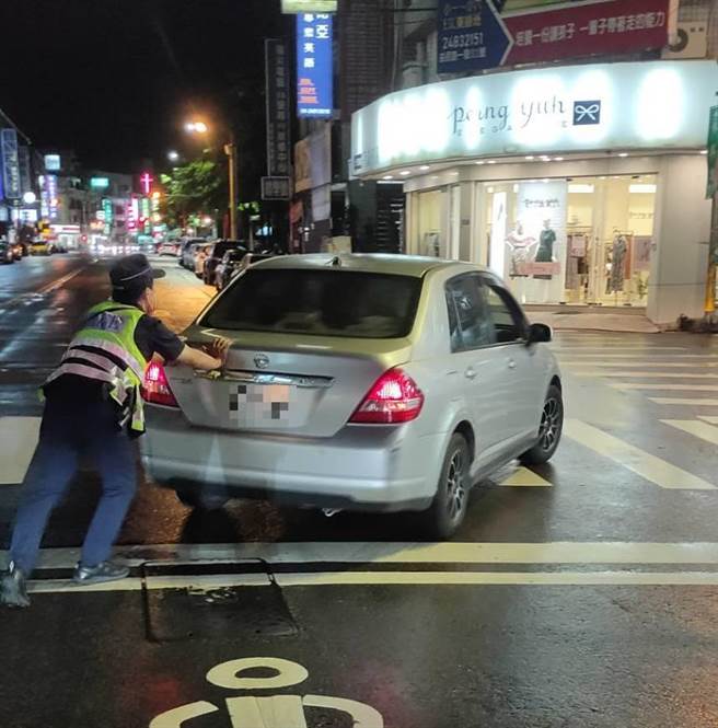 一輛汽車故障卡十字路口，員警化身大力士推離避險。（民默提供／盧金足台中傳真）