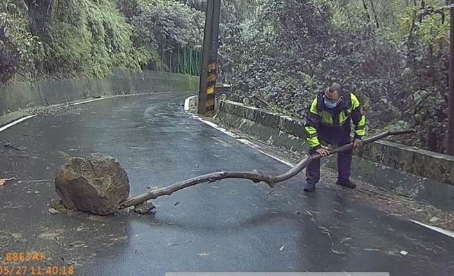 员警吴嘉仁灵机一动，以木头及石块产生支点将该落石撑起。（民眾提供）