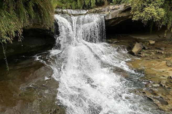 ▲眼镜洞瀑布因岩壁上的两处凹洞如眼镜般而得名。　图：新北市政府观光旅游局／提供