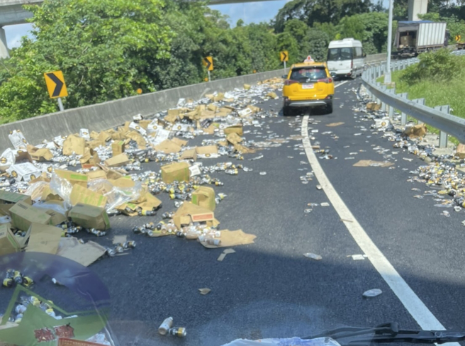 國道1號機場系統接國2西向匝道口30日上午發生貨車載運物品掉落，滿地都是啤酒罐與飲料罐。（翻攝自記者爆料網）