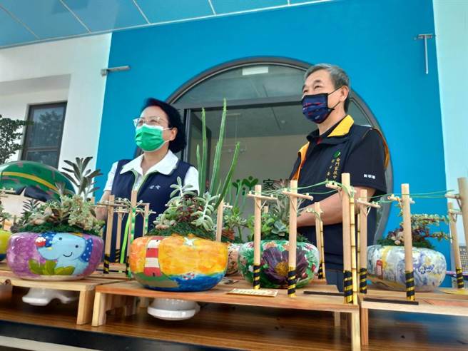 台电金门区营业处运用退役的碍子，组合赏心悦目的盆栽植物。黄甘杏处长（左）今早将同仁巧手下的爱心绿植30份转赠金门家扶中心。（金门家扶中心提供）