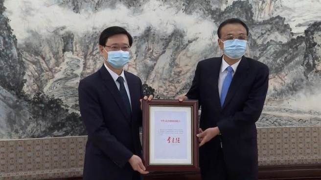 李克强（右）向李家超颁国务院令，任命李家超为香港第六任行政长官。（中新社）