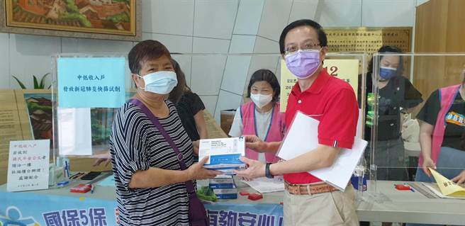 淡水區長巫宗仁（右）發送快篩劑給弱勢戶。（新北市社會局提供）