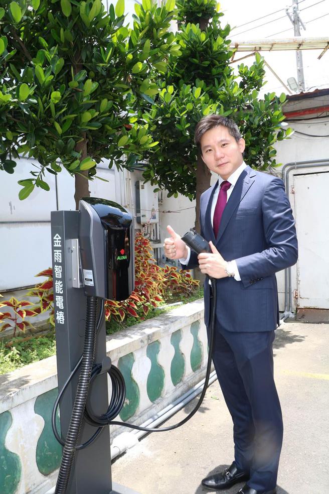 （金雨董事长卓政懋，31日手拿充电枪，亲自示范操作位于公司大门口旁的「金雨智能电桩」。图／刘朱松）