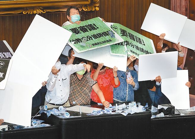 立法院院会30日处理攸关国务机要费除罪化的《会计法》修正案，不满民进党团要强行表决通过，国民党立委们丢杯水到主席台表达抗议，在台上的民进党立委们则用纸板抵御杯水攻击。（刘宗龙摄）