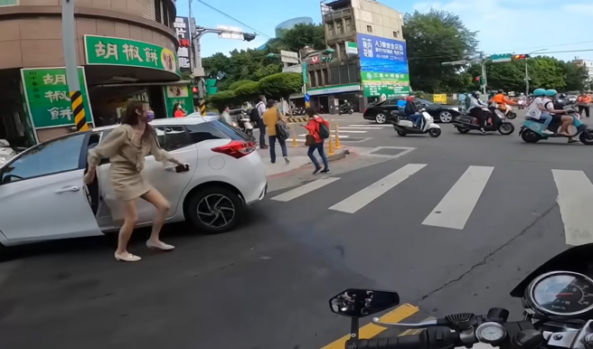 長腿妹駕車左轉害直行機車擦撞，義交趕緊向前指揮交通保護傷者，長腿妹也積極的關心倒地騎士。（翻攝自YouTube頻道「WoWtchout - 地圖型行車影像分享平台」）