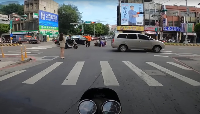 長腿妹駕車左轉害直行機車擦撞，義交趕緊向前指揮交通保護傷者，長腿妹也積極的關心倒地騎士。（翻攝自YouTube頻道「WoWtchout - 地圖型行車影像分享平台」）