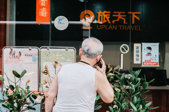 北市为数不多仍运营一楼店面的旅行社，正苦撑等待国旅市场回春，店外一位民眾探头观看店内促销资讯却没踏入店里。(郭吉铨摄)