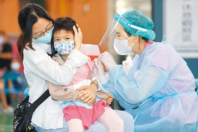 許多家長反映，滿5歲的幼童不好預約BNT疫苗，桃園市政府宣布5月31日起兩天在4所學校增設5至6歲兒童的疫苗快打站，圖為桃園區青溪國小快打站施打BNT疫苗，一位小女生依靠在母親身邊完成疫苗施打。（陳怡誠攝）