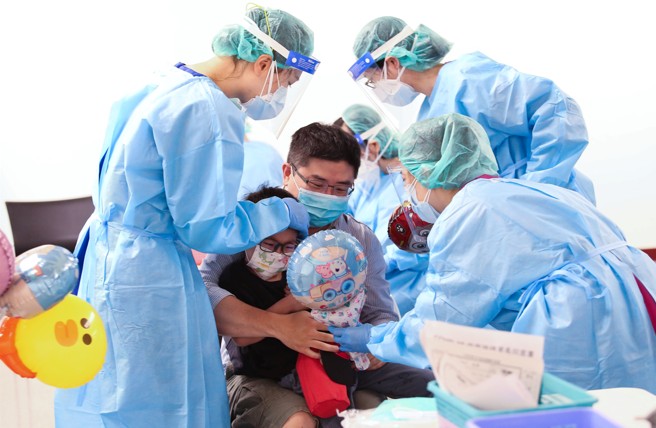 民眾帶小孩前往中正紀念堂接種疫苗，醫護送上氣球安撫。（陳俊吉攝）