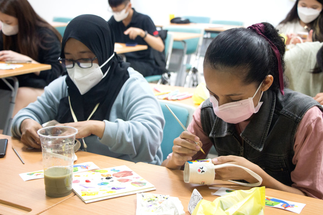 义大境外学生在杯套上手绘画出端午节意象，透过活动认识端午节的文化意涵。(图/义守大学提供)