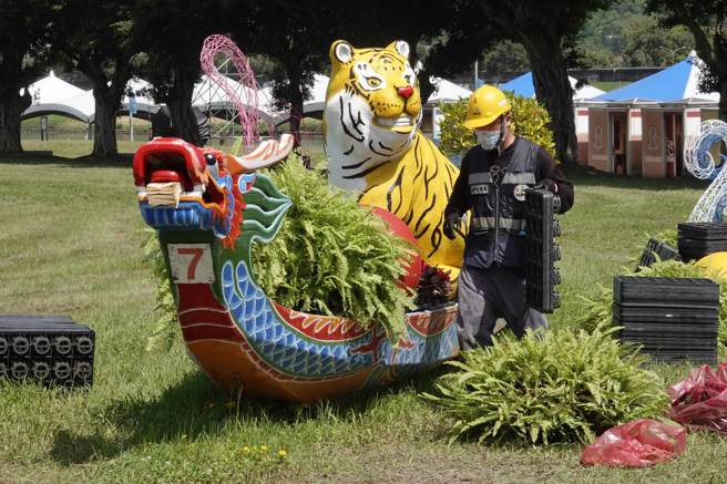 端午连假期间各地多为多云到晴的天气型态，白天高温可达34度，感受上闷又热。图为工作人员在大佳河滨公园装置龙舟园艺造景，为明（3日）台北国际龙舟锦标赛开幕做准备。（黄子明摄）