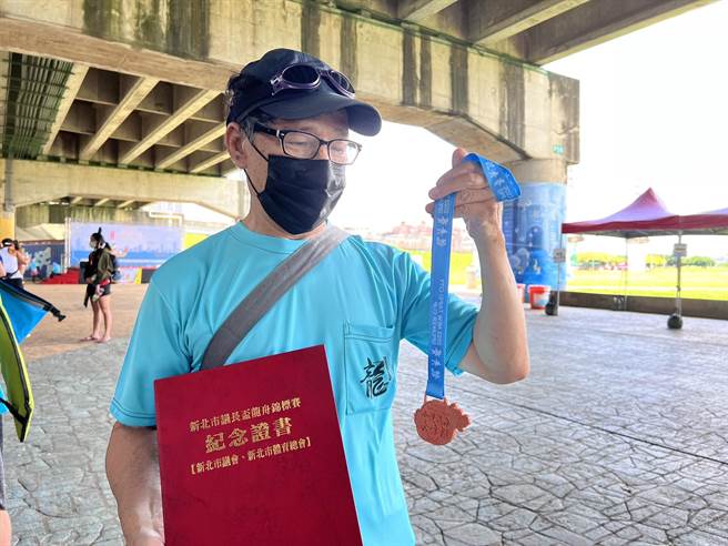 「青潭堰快乐队」队员范金龙受访时拿着奖牌，脸上藏不住笑意。（李奇叡摄）