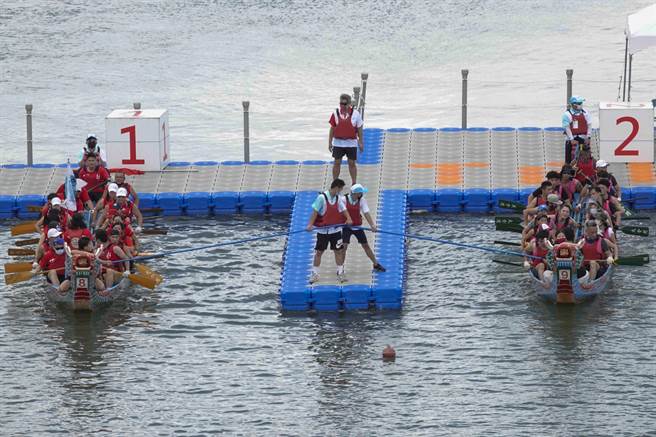 参赛队伍从出发的浮动码头就被分配在不同水道，为确保各龙舟能站在同一起跑点，以及位居水道中心以免碰撞，码头必须有专人持长竹竿固定龙舟位置。（黄子明摄） 