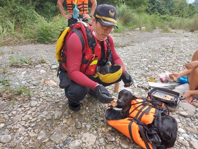  花莲县消防局接获民眾报案，黄金峡谷三栈溪有黑狗受困岩缝中，经查看小黑狗右前脚已截断，消防人员以救生衣充当浮板，与民眾合力将小黑狗抬至三栈溪出口，现场游客也拿出麵包、烤肉为小黑狗补充体力。（图/ 中央社）
