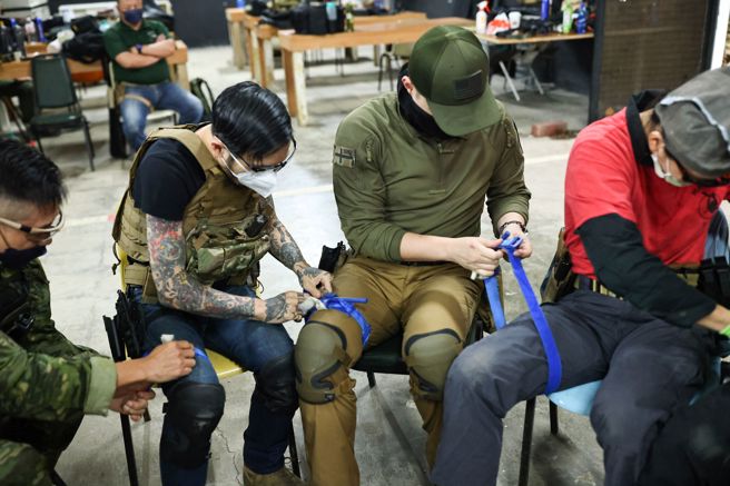 學員們在急救訓練時練習將止血帶放在彼此的腿上。(圖/路透社)