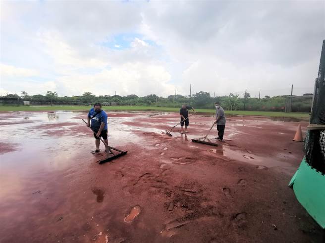 台南市麻豆區柚城棒球隊家長與志工趁著雨勢暫停，整平棒球場內紅土。（劉秀芬攝）