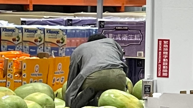 好市多一名身穿灰大为挑选西瓜，在没脱鞋的情况下，整个人爬到西瓜堆里。（图／翻摄自爆怨公社）