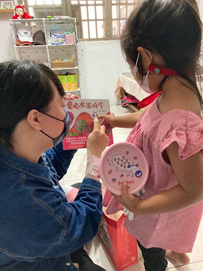 社工将信谊基金会600份礼袋送到台东县脆弱家庭孩童手中，亲子掩不住喜悦和兴奋立刻拿起图画书开始读起来(信谊基金会提供)