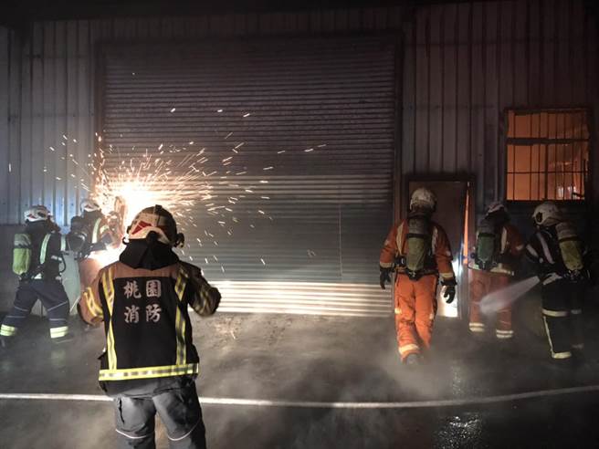 消防人員鋸開鐵門緊急布水線灌救。（桃消防第二大隊提供／蔡明亘桃園傳真）