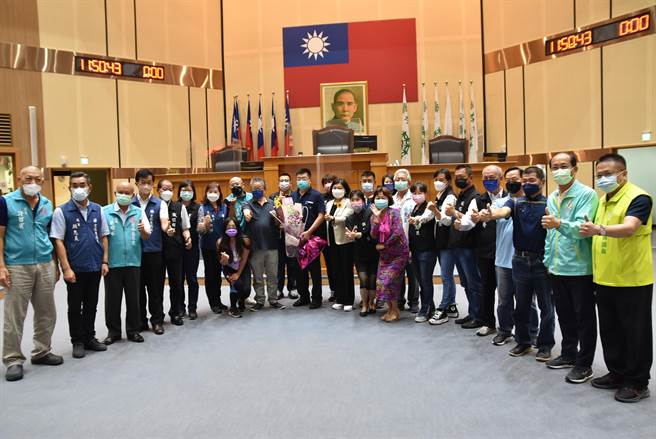 云林县议会议事组主任吴国正（中间捧花者）本月底届龄退休，今（9日）定期会是他朗读议案的最后一天，议长沈宗隆（左九）率跨党派议员起立鼓掌并献花。（周丽兰摄）。