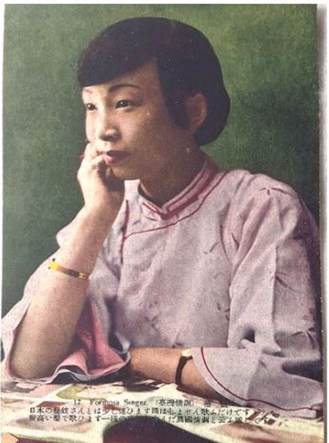 图片中的年轻艺姬身着唐装短挂，衣服以素面简单为主，没有浓妆艷抹，神态自若，以右手托腮正在沉思当中，这姿势恰好露出左右手腕上所佩戴的手表及金色手饰品，象徵她所拥有的身分和地位。