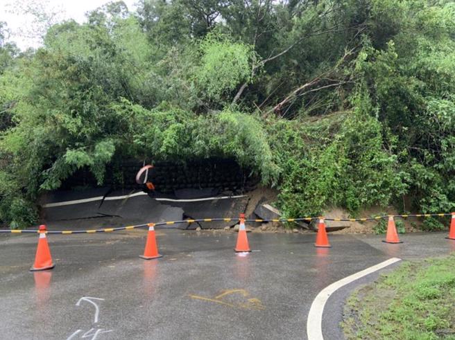 苗栗县造桥乡平兴村苗12线道路9日疑因大雨冲刷山坡土石松动造成走山，大片树林和土石滑落到马路，苗栗县警察局竹南分局获报已派员摆放交通锥等交通管制设备，10日上午仅开放单线双向通行。（图/ 中央社）