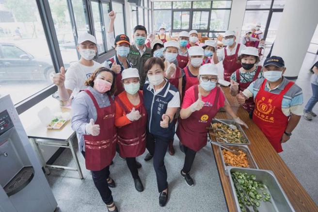新竹市副市長沈慧虹（前左3）10日至南福長青會共餐食堂關心運作情形，除穿上圍裙煮菜，也和歌唱班長輩寒暄、關心志工，幫長輩打飯、享用美味佳餚。（圖/ 中央社）

