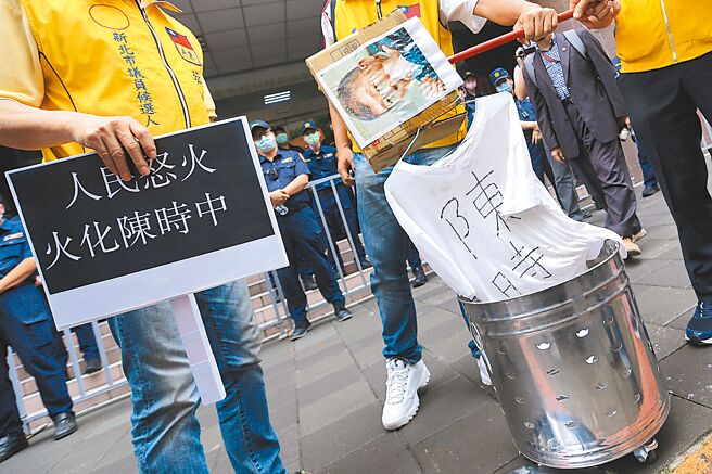 数名新党市议员参选人9日到卫福部疾管署，抗议近日来引发争议的新冠肺炎确诊死亡者遗体火化规定，并举火把作势要烧掉卫福部长陈时中的肖像，高喊「人民要善终，火化陈时中」，遭警方阻止，随后将肖像道具放入金纸桶中，以灭火器喷洒表达不满。（黄世麒摄）