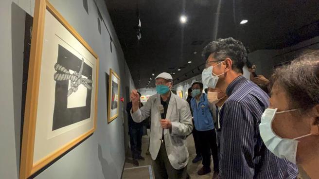 「福临美至－2022廖修平作品金门展」在金门县文化局展出，国际知名版画家廖修平（左）向金酒公司董事长黄怡凯（右2）等人导览画作。（图 / 中央社）