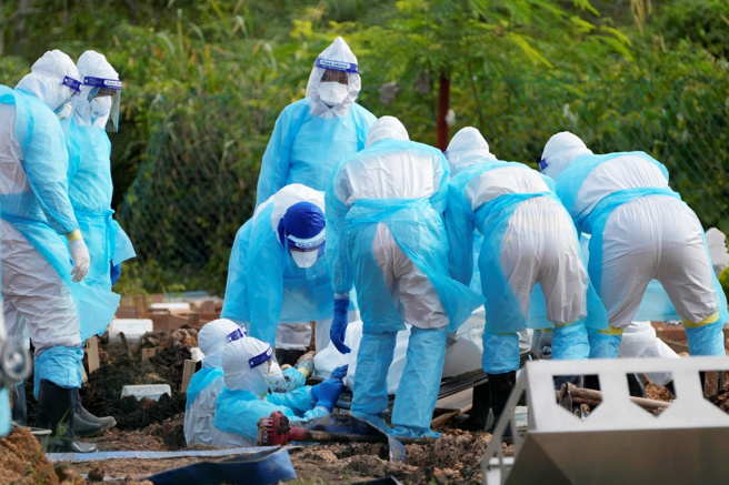 世界卫生组织（WHO）建议，应尊重新冠死者尊严、文化及宗教传统，避免仓促弃置新冠死者遗体。图为2021年8月，马来西亚的卫生人员穿着防护服，安葬一名新冠死者。（图／美联社）